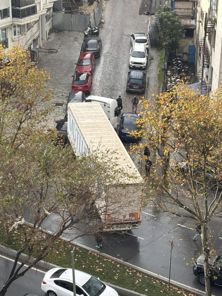 Kamión uviaznutý na úzkej ulici, obklopený zaparkovanými autami a stromami. Prekážky v mestskej doprave.