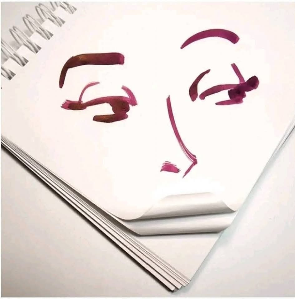 Abstraktný portrét očí a nosa namaľovaný na strane skicára, vytvára zaujímavý 3D efekt prehnutím papiera.