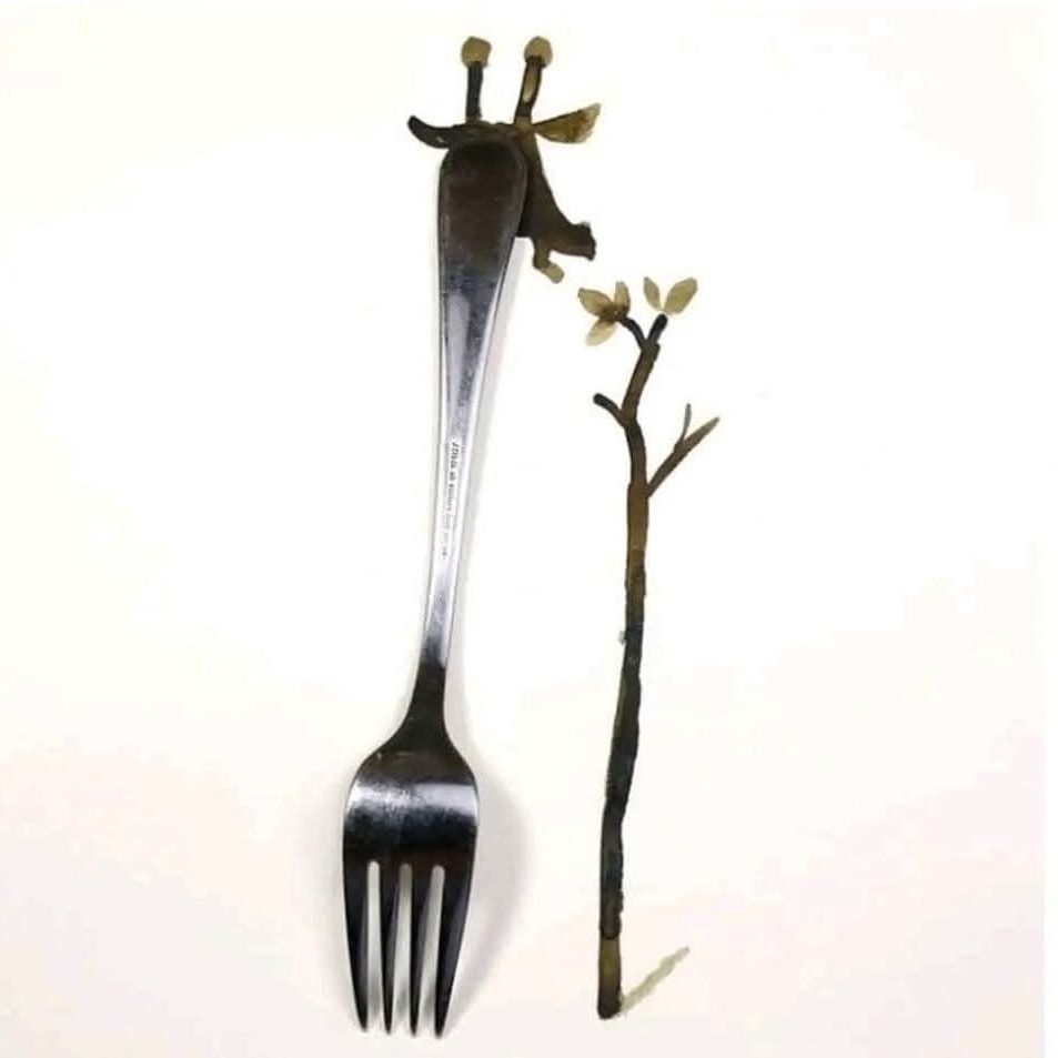 Vidlička kreatívne upravená do tvaru žirafy pri strome na bielom pozadí.