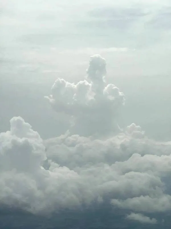 Oblak na oblohe v tvare figúry, pripomínajúci ruky a hlavu, vynikajúci na zamračenom pozadí.