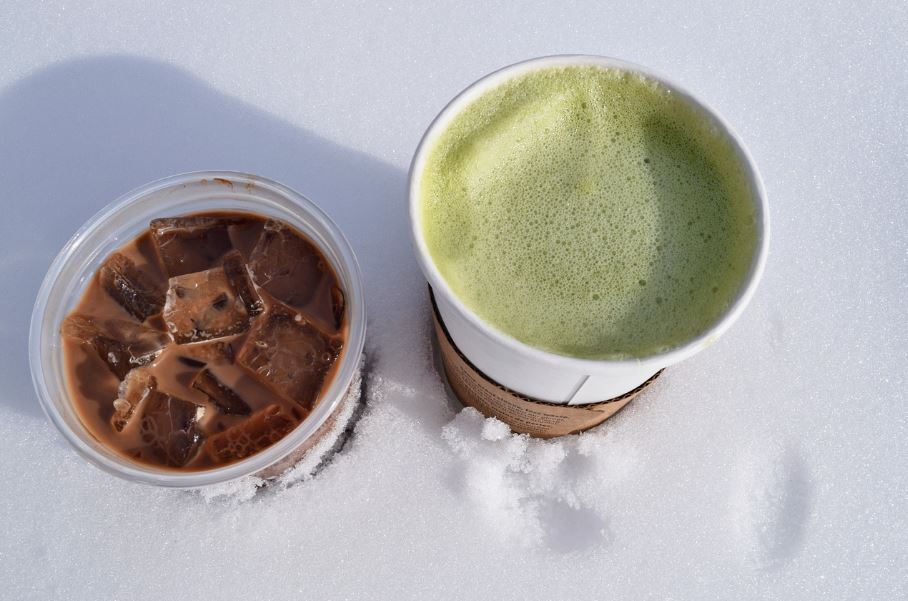Zelený čaj matcha a ľadová káva na snehu, kontrast chutí a farieb.
