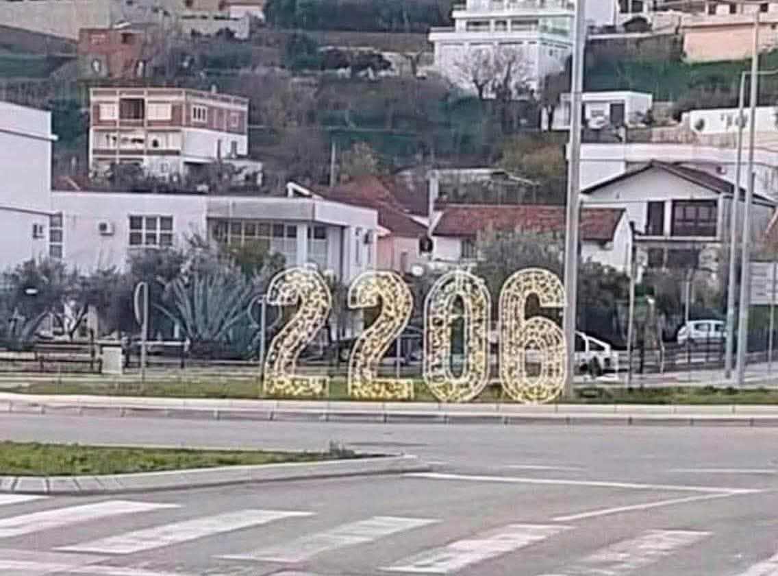 Osvetlené čísla „2206“ na kruhovom objazde v mestskom prostredí s obytnými budovami v pozadí.