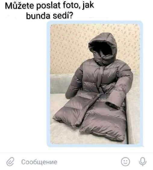 Šedá bunda na gauči nesená len vzduchom, bez osoby, srandovný spôsob ukázania, ako bunda sedí.