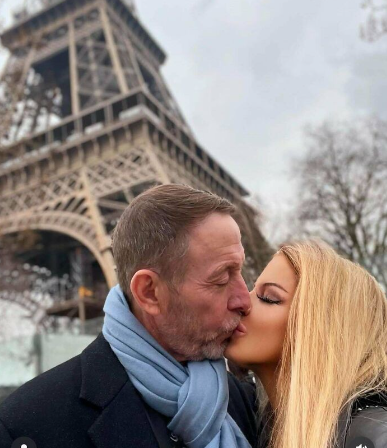 Pár bozkávajúci sa pred Eiffelovou vežou v Paríži počas zamračeného dňa.