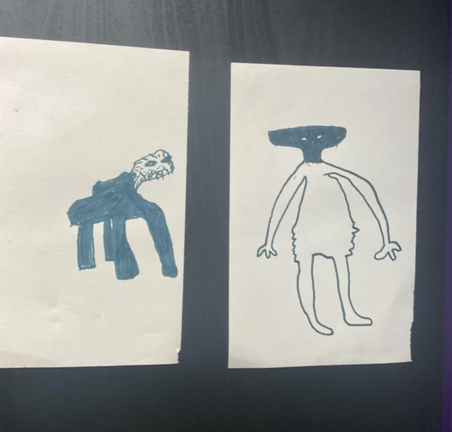 Detské kresby dvoch zvláštnych bytostí na bielom papieri na tmavom pozadí.