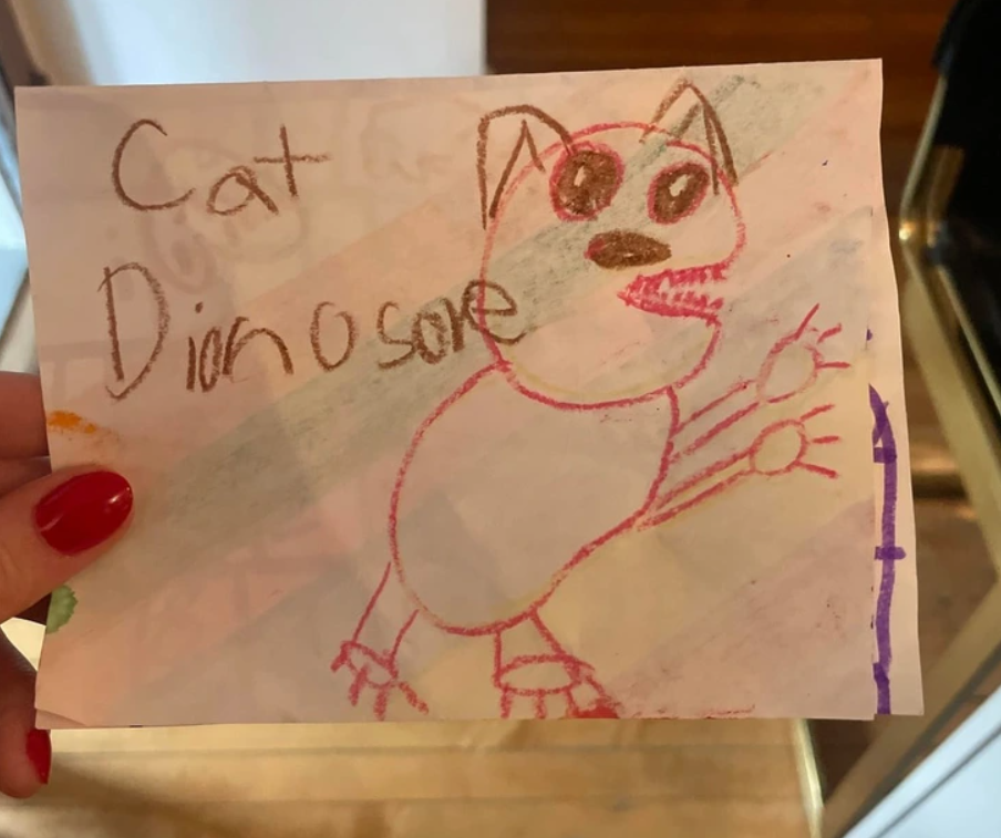 Detská kresba kombinácie mačky a dinosaura na bielom papieri.