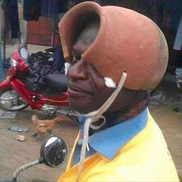 Osoba na motorke nosí na hlave hlinený kvetináč, kreatívny prístup k ochrane hlavy.