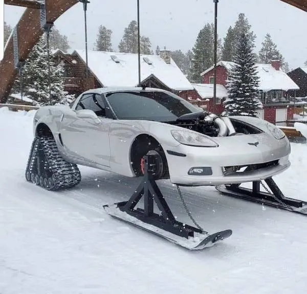 Športové auto s lyžami a pásmi na zimu, zasnežená krajina, upravené vozidlo pre snehové podmienky.