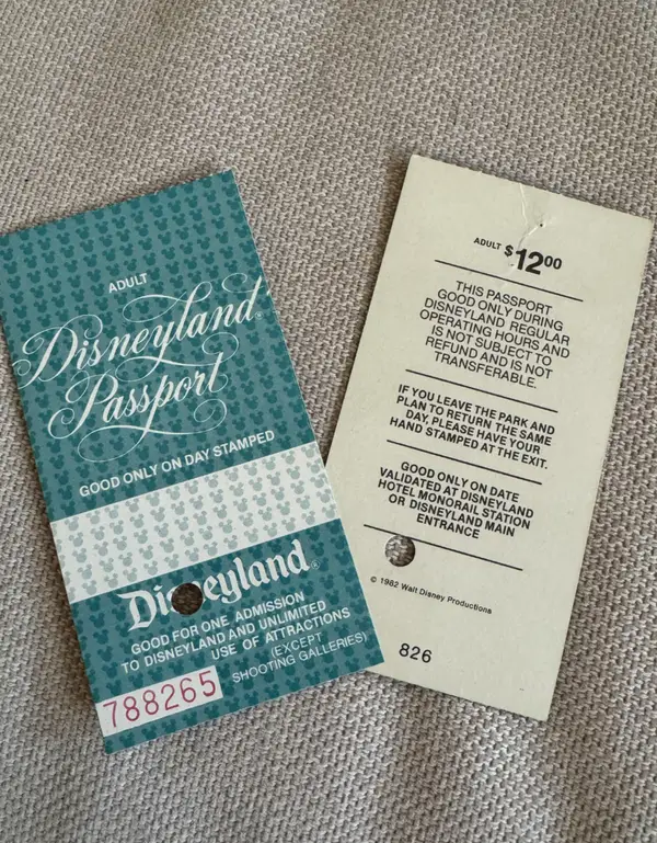 Vintage Disneyland lístok z roku 1982 s cenou 12 dolárov a podmienkami použitia na šedom povrchu.