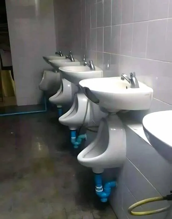 Umývadlá umiestnené nad pisoármi v netradične navrhnutej verejnej toalete.