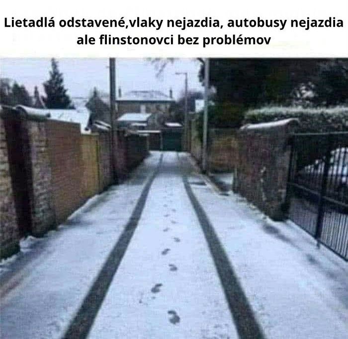 Snehová pokrývka na ceste, stopy vozidla a chodcov, vtipný odkaz na Flinstonovcov počas zimného nečasu.