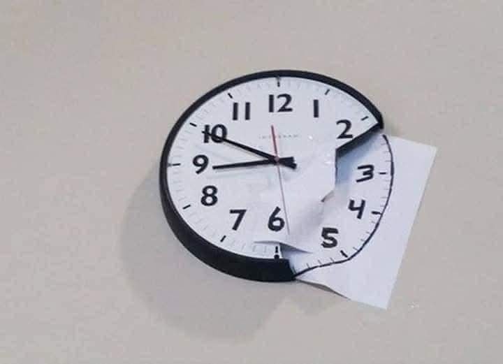 Nástenné hodiny s poškodeným ciferníkom, kde je časť nahradená papierom, ukazujú čas 10:09.
