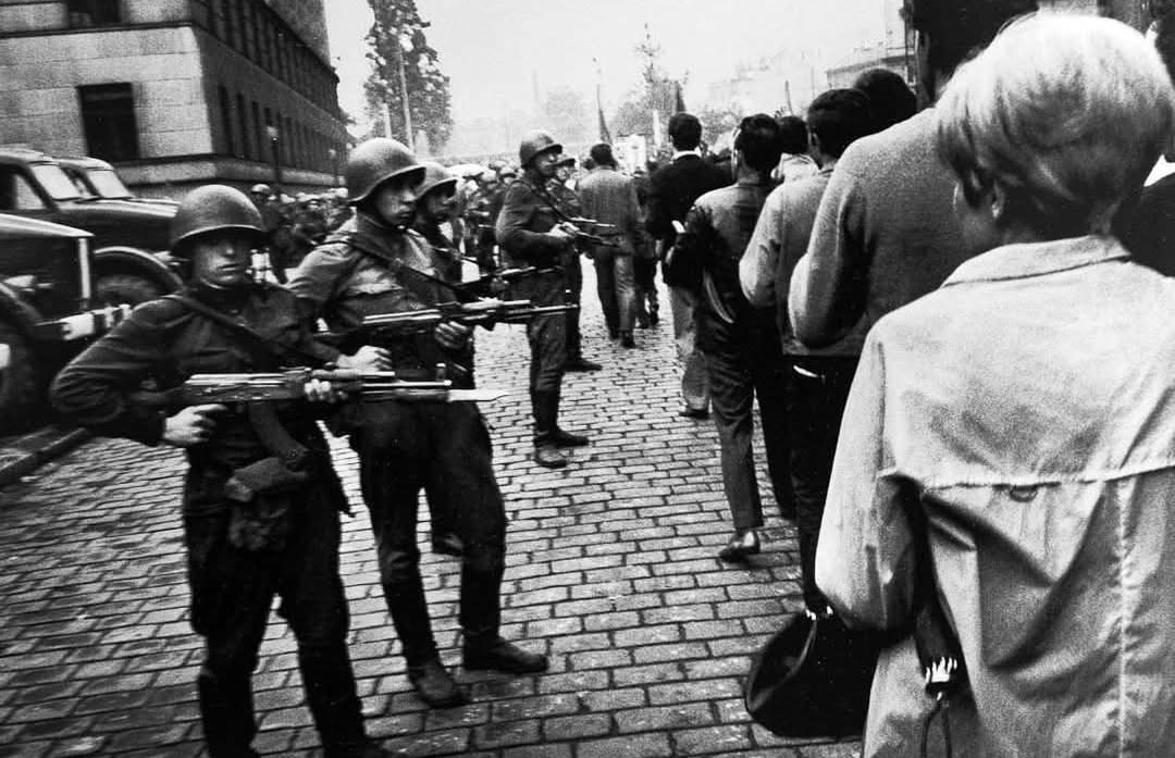 Nepokoje na ulici, vojaci s puškami tvárou v tvár davu civilistov. História a konflikt na kockovanej dlažbe.