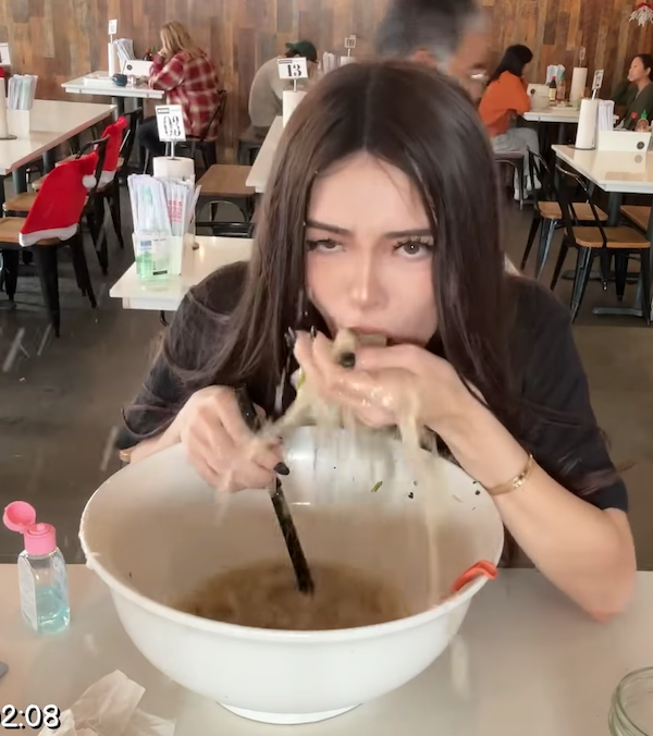 Žena rýchlo konzumuje rezance z veľkej misy v reštaurácii.