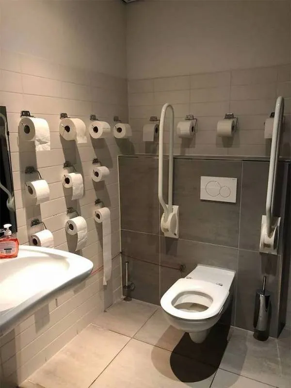 Kúpeľňa s množstvom držiakov na toaletný papier okolo toalety a umývadla.