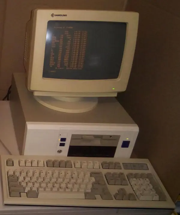 Starý stolný počítač s CRT monitorom, disketovou mechanikou a klávesnicou na stole.