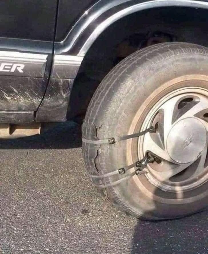 Auto pneumatika s improvizovanou opravou použitím káblových viazadiel na hladkej asfaltovej ceste.