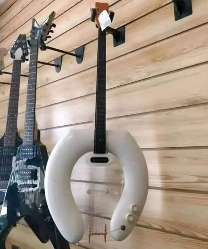 Gitara s netradičným tvarom záchodovej dosky na stene v obchode s hudobnými nástrojmi.