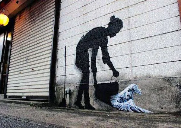 Graffiti ženy vylieva vodu, ktorá sa mení na vlnu; umelecké dielo na bočnej stene budovy.