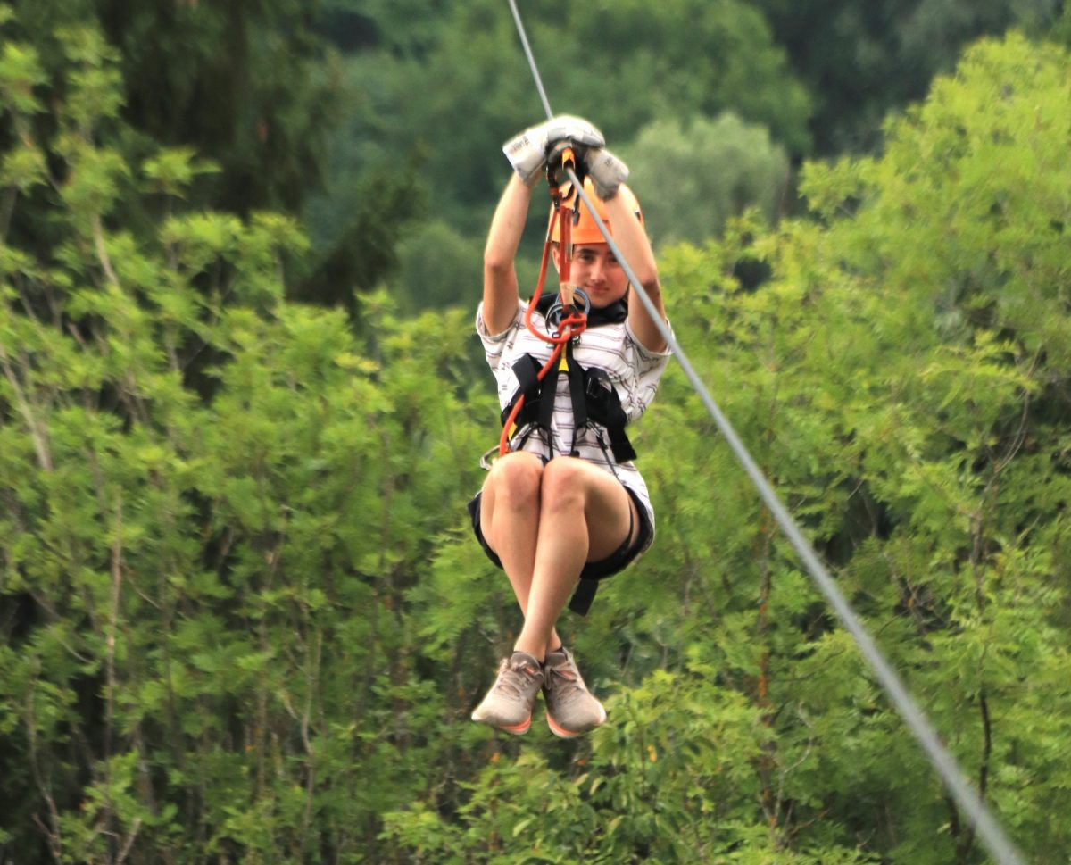 Osoba na lanovej dráhe v lese, zažíva adrenalínový zážitok na zipline.