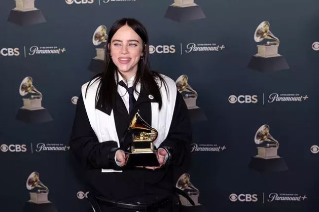 Osoba držiaca cenu Grammy na červenom koberci s logami CBS a Paramount+ na pozadí.