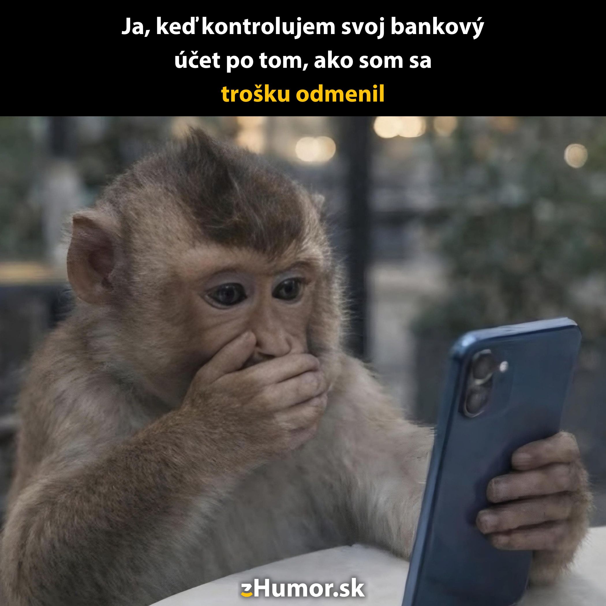 Opička drží telefón a zakrýva si ústa rukou, prekvapená z obsahu, ktorý vidí.