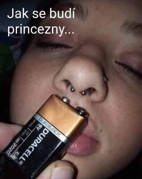 Osoba so zavretými očami a prepichnutým nosom, vedľa úst drží batériu; vtipný moment.