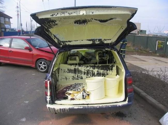 Auto s otvoreným kufrom, v ktorom sú rozliate vedrá s bielou farbou.