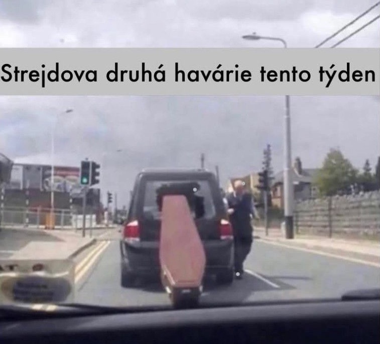 Auto na ceste nesie rakvu napoly vyčnievajúcu zo zadného okna s nápisom „Strejdova druhá havária tento týždeň“.