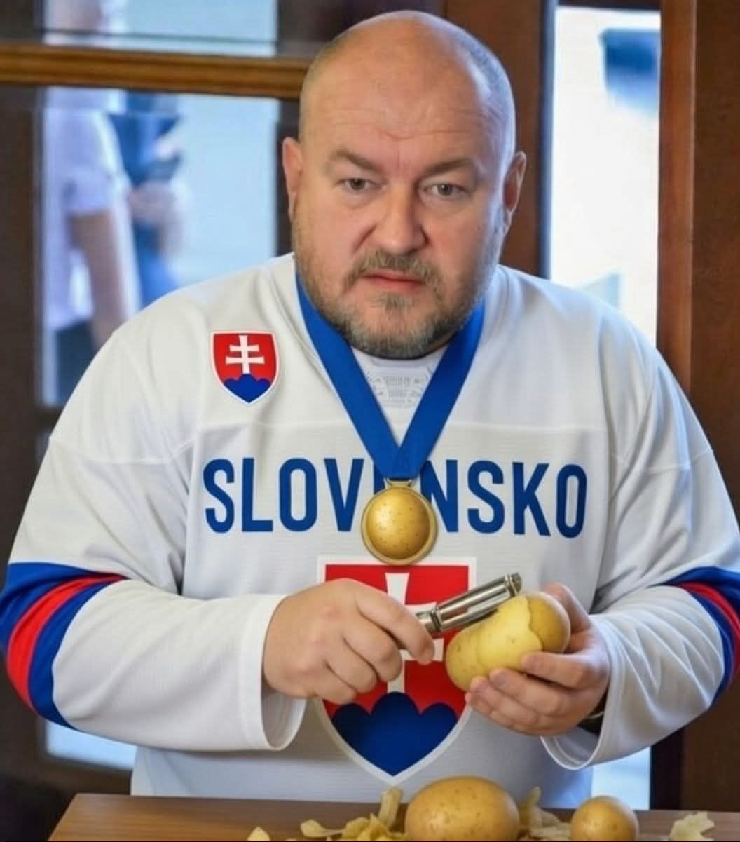Muž v hokejovom drese Slovenska škrabajúci zemiaky, s medailou na krku a vážnym výrazom tváre.