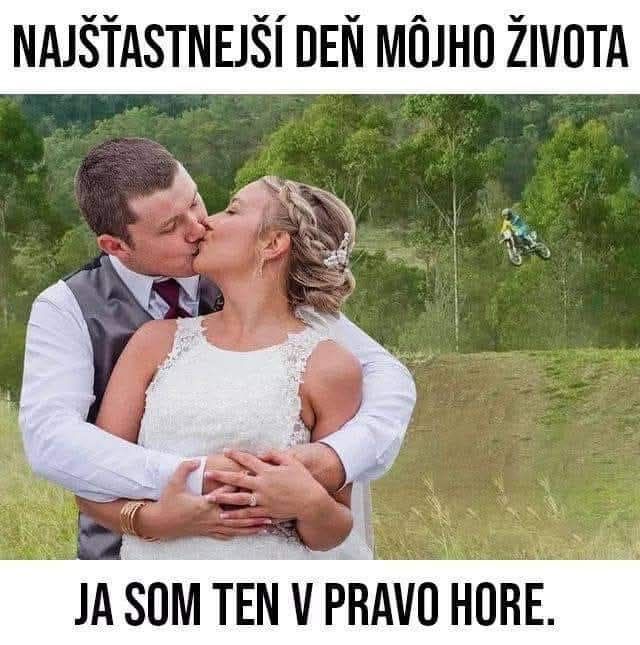 Novomanželský pár sa bozkáva, zatiaľ čo v pozadí motorkár skáče cez svah. Humoristický moment na svadbe.