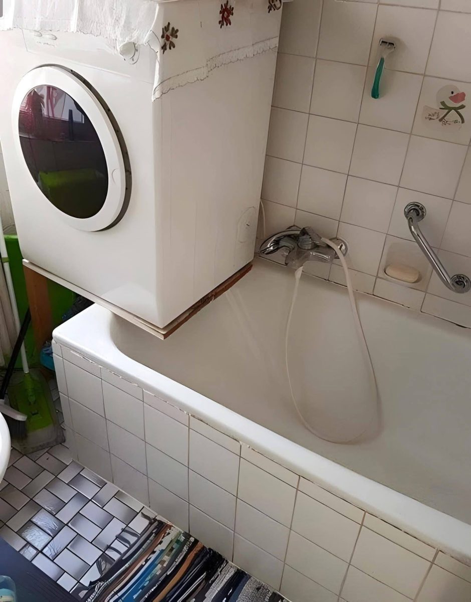 Sušička nad vaňou v malej kúpeľni s bielymi obkladačkami a podlahou.