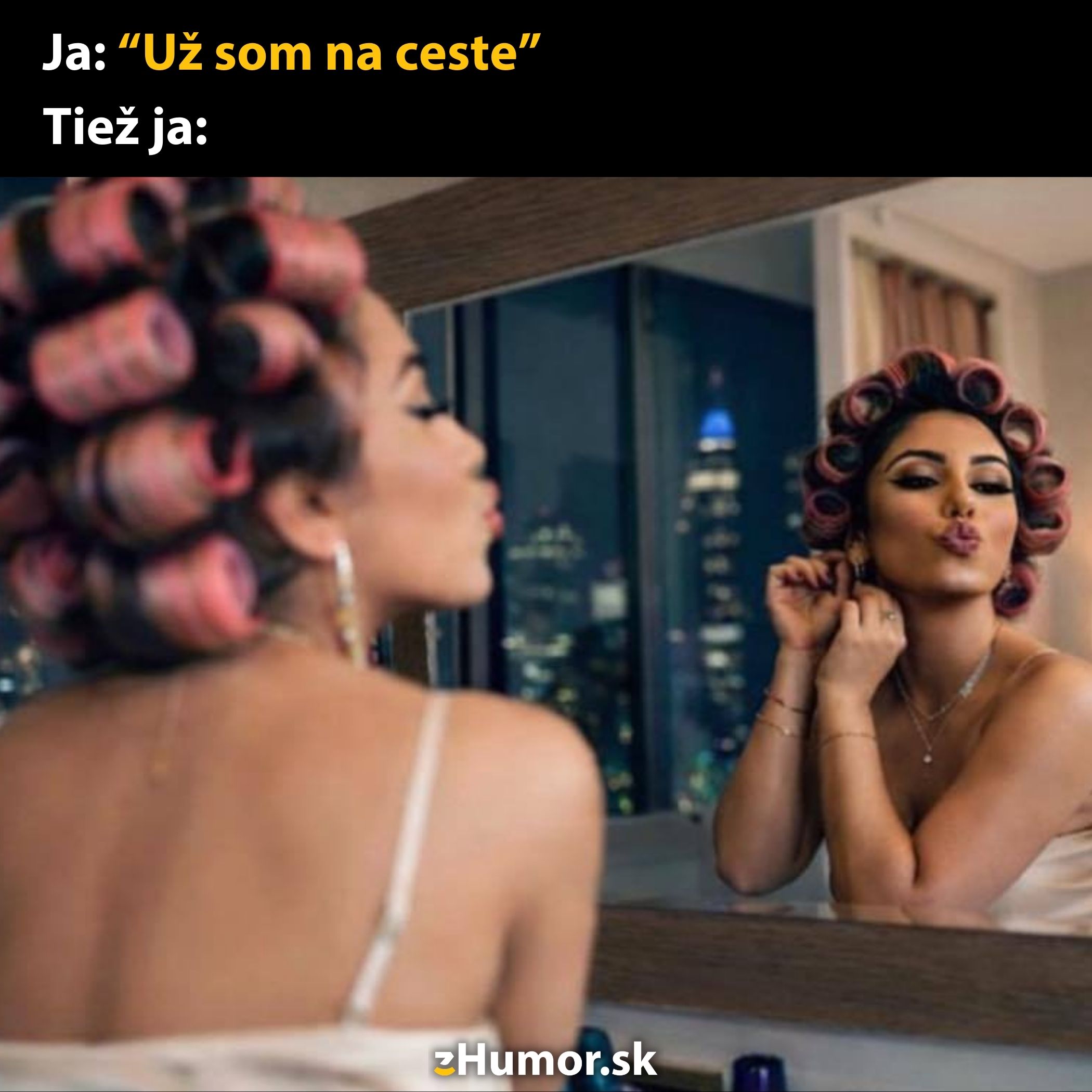 Žena s natáčkami púšťa bozk do zrkadla, vtipný kontrast s tvrdením, že už je na ceste von.