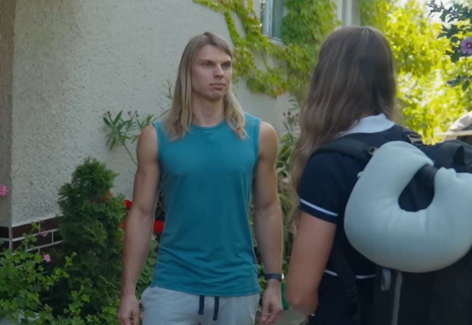 Dve osoby diskutujú vonku pred domovom, obkolesení zeleňou a kvetmi.