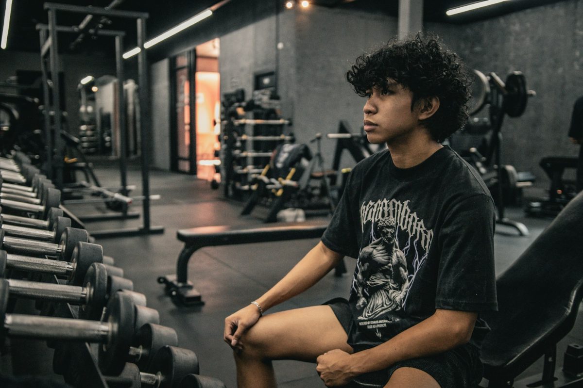 A young man sitting on a bench in a gym