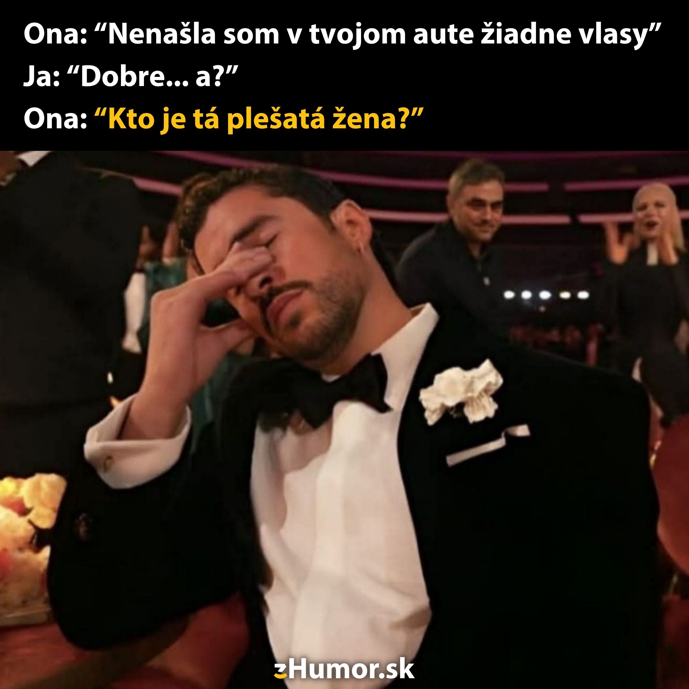 Muž v smokingu si zúfalstvo drží hlavu, zatiaľ čo žena s blond vlasmi reaguje v pozadí.