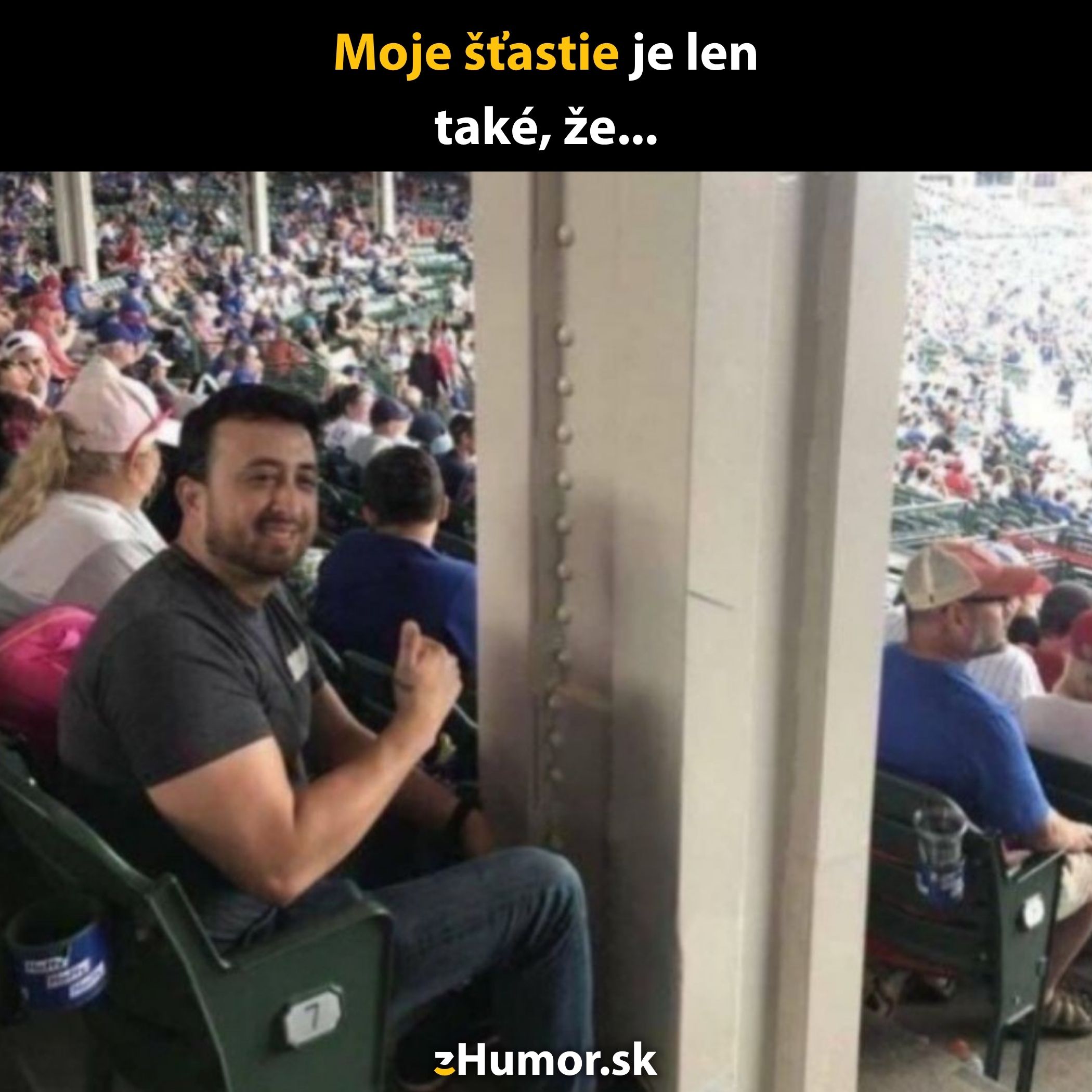 Muž sedí na športovom podujatí s obmedzeným výhľadom kvôli stĺpu, úsmev reprezentuje humor smoliara.