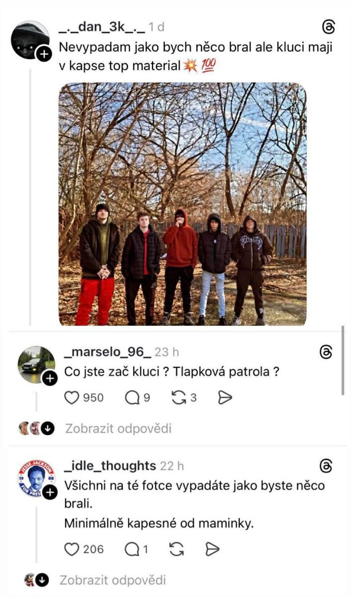 Skupina piatich mladíkov v prírode pri plote, každý oblečený v zimnom oblečení, niektorí majú kapucne.