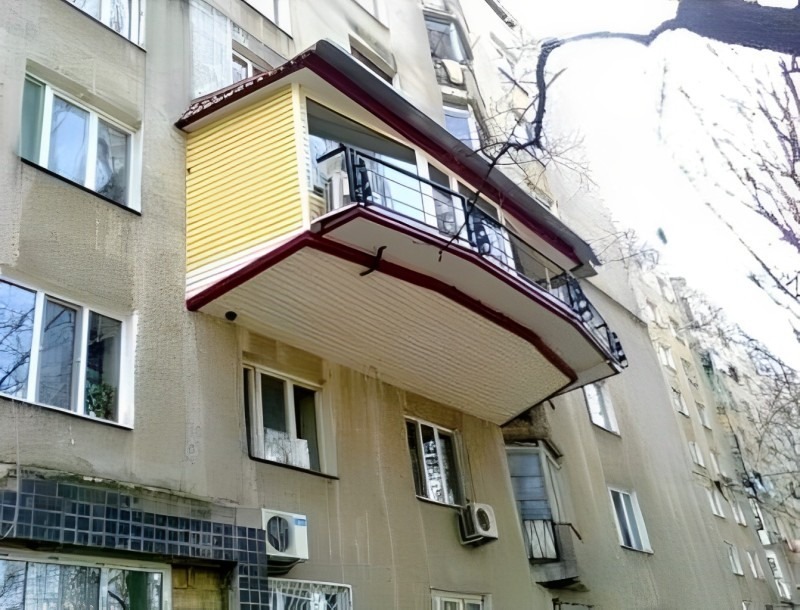 Balkón s farebnými panelmi na staršej budove, modernizovaný dizajn s novým zábradlím, pohľad na mesto.