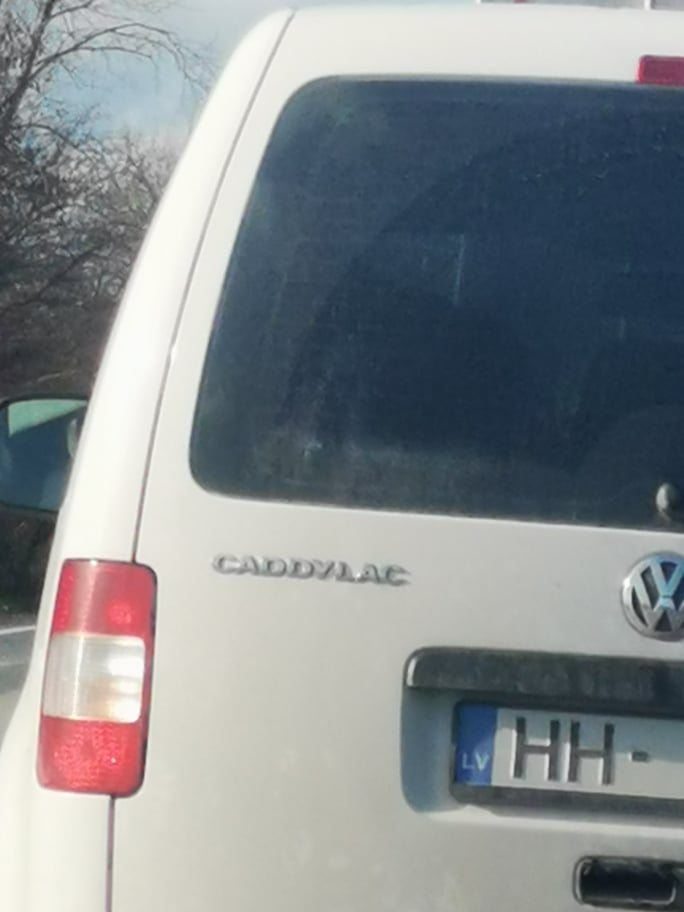Biele vozidlo Volkswagen Caddy so zábavnou úpravou názvu na CADDYLAC na zadnej strane.