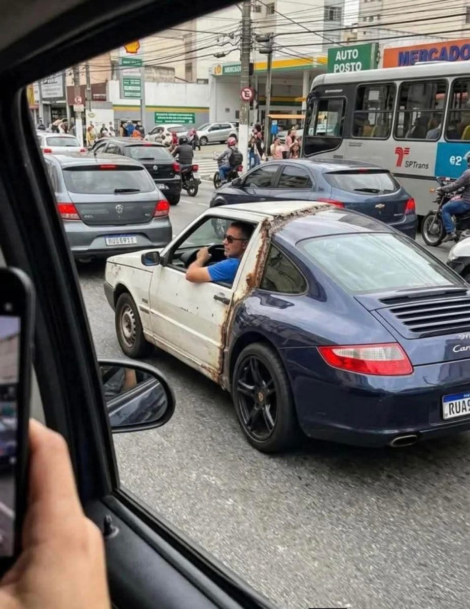 Auto s kombináciou karosérií v zápche na mestskej ulici, vodič sleduje premávku.