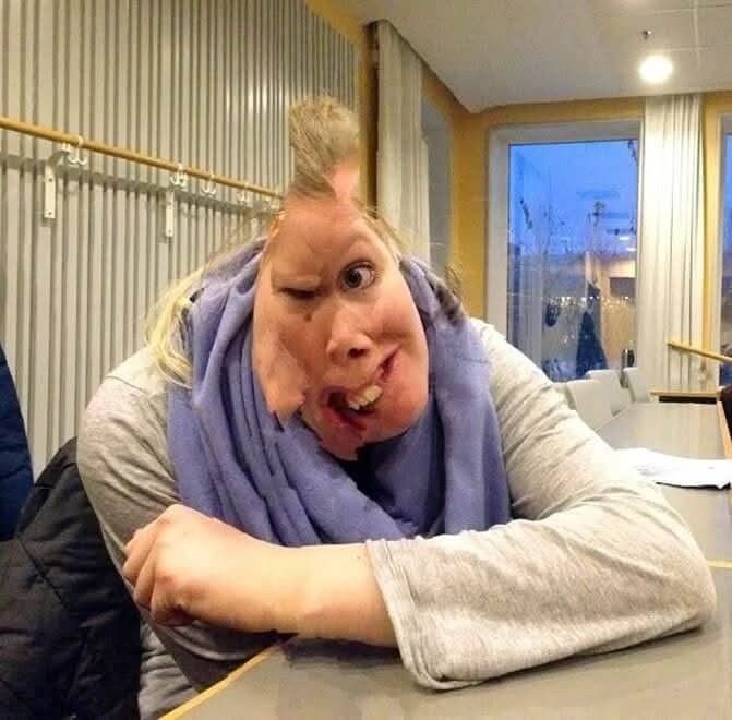 Osoba s rozmazanou tvárou v miestnosti, efekt skreslenia obrazu, šedý sveter a modrý šál.