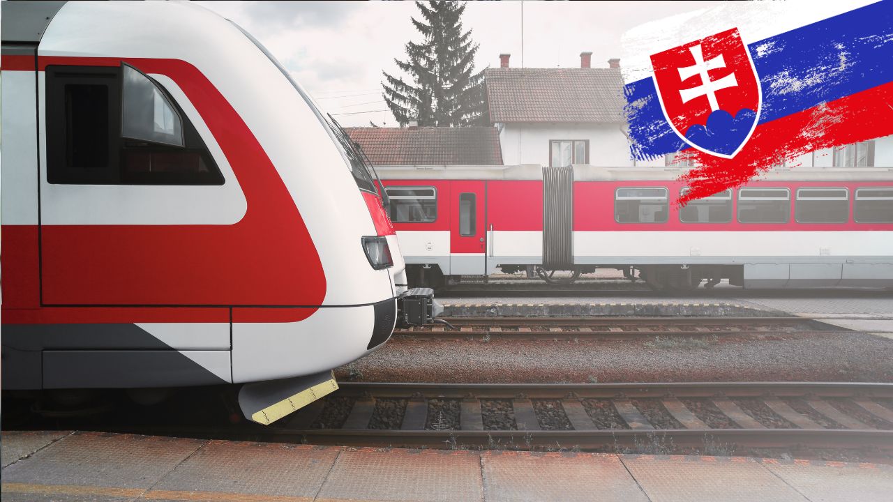 Slovenský vlak na stanici, v pozadí budova s lesom, vo farbách Slovenska.