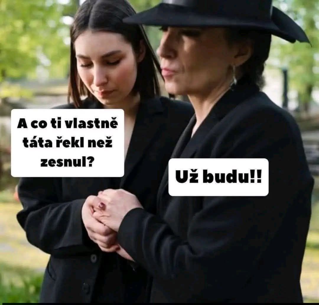 Dve ženy v čiernom, držia sa za ruky na cintoríne, rozprávajú sa vo vážnej atmosfére.
