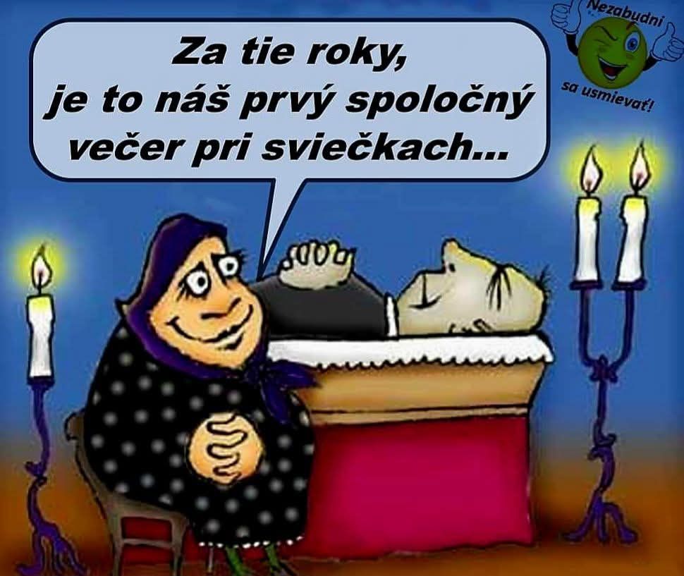 Staršia žena s úsmevom sedí pri rakve so zosnulým, obklopení sviečkami.