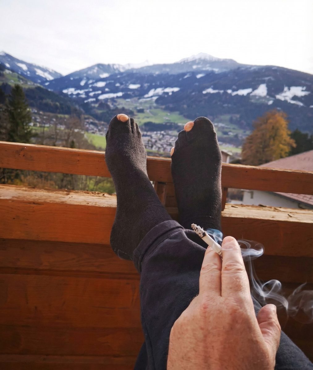 Relax na terase s cigaretou a výhľadom na zasnežené hory.