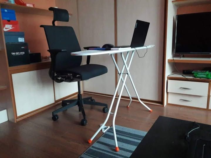 Pracovný kútik s čiernou stoličkou, sklápacím stolíkom a laptopom v útulnej miestnosti.
