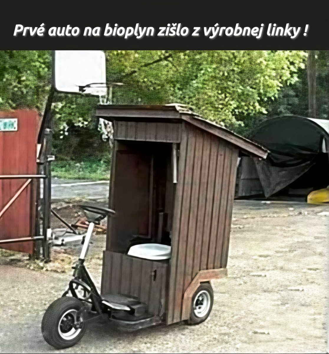 Upravená trojkolka s drevenou konštrukciou pripomína záchod, ako ekologické vozidlo na bioplyn na dvore.