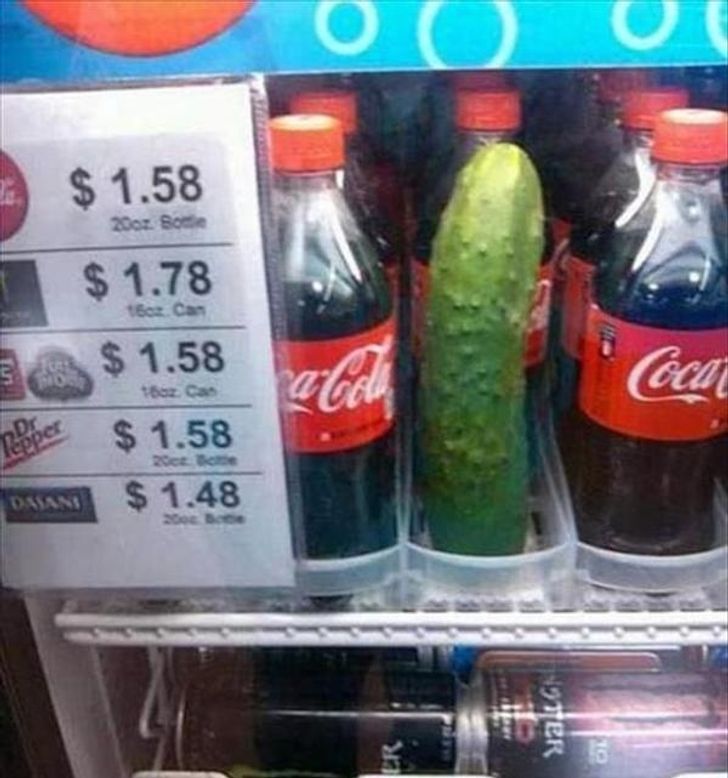 Automat na nápoje s fľašami Coca-Coly, medzi ktorými je nečakane umiestnená uhorka.