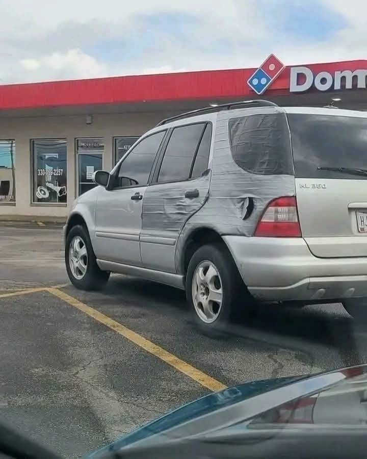 Auto opravené lepiacou páskou zaparkované pred pizzeriou Domino's.